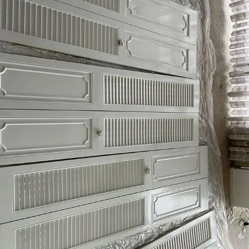 Freshly painted louvered cabinet doors laid out to dry
